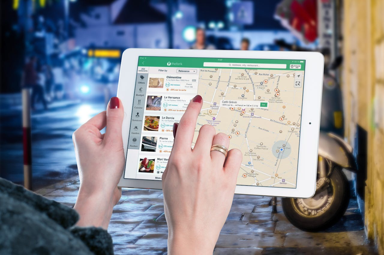 services-02 Hands using a digital map on a tablet in an urban setting at night, illustrating navigation and technology.